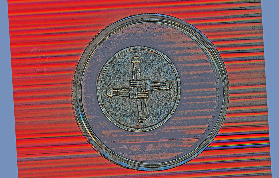 Resting atop an untraviolet photographic filter is the Medal of Saint Brigid and underneath are two channels of light one black the other red